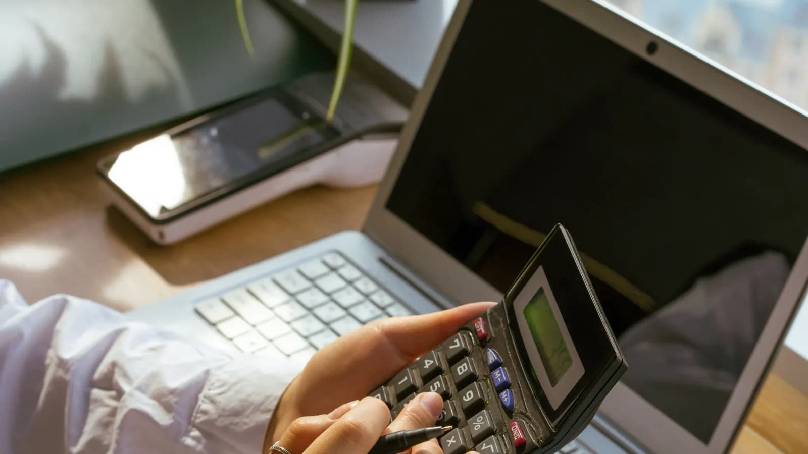 Person calculating a rate at a desk with a laptop