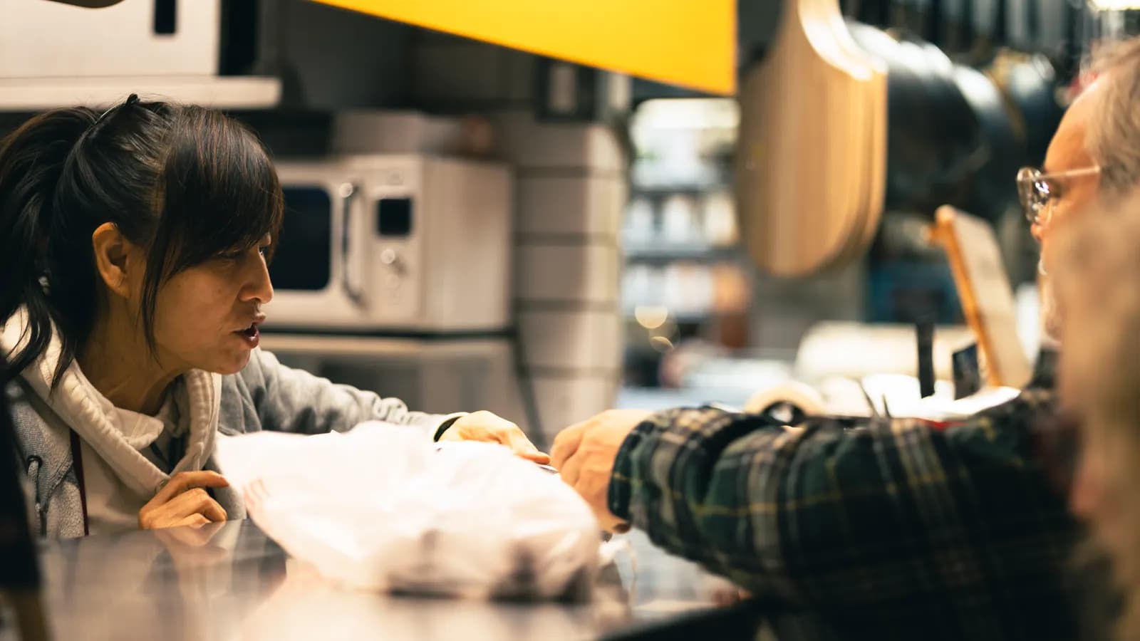 Shopkeeper handing a product to a customer at the counter